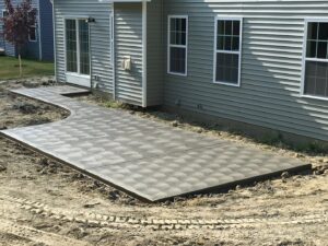 A large patterned concrete patio next to a house, recently completed by Paris Brothers & Company, Inc in Erie, PA