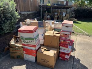 A large pile of cardboard boxes, including U-Haul and Office Depot boxes, ready for general junk removal by Grawe Junk & Demo in Arlington, TX.
