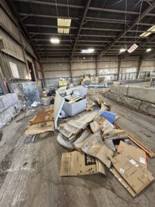 A large pile of cardboard boxes and various debris on the floor of a warehouse, ready for removal by Reno Junk Pros in Reno, NV.