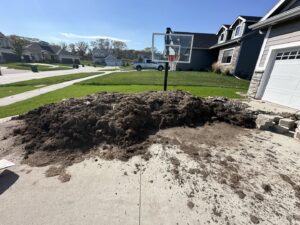 A large pile of dirt and mulch on a driveway, ready for removal by Vargas Junk Removal & Dumpster Rentals in Urbandale, IA.