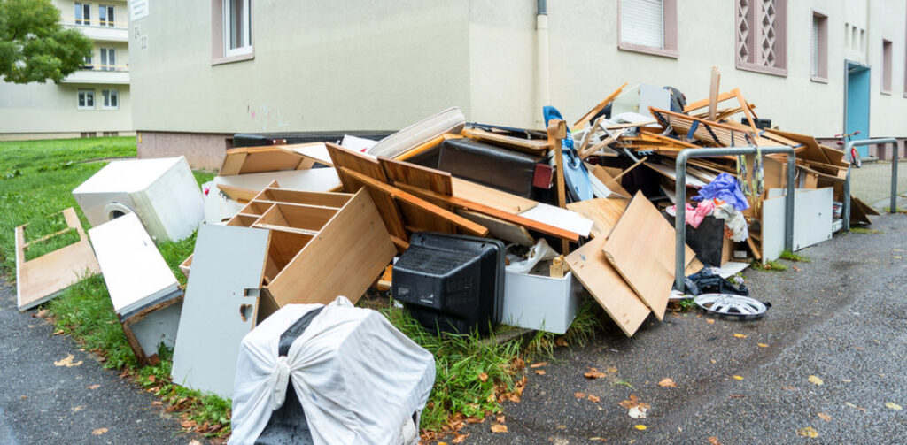 A large pile of household debris, furniture, and various items next to a building, ready for Junk Unlimited Junk Removal in Laurel, MD.