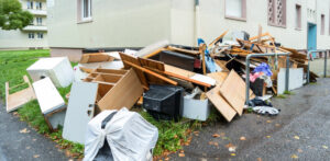 A large pile of household debris, furniture, and various items next to a building, ready for Junk Unlimited Junk Removal in Laurel, MD.