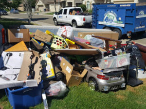 A large pile of various household junk, boxes, and furniture on a lawn, ready for removal by Junk Away & Cleaning in Sacramento, CA.
