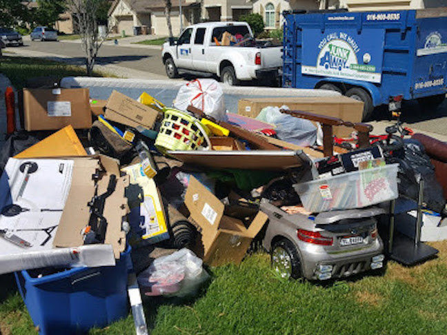 A large pile of various household junk, boxes, and furniture on a lawn, ready for removal by Junk Away & Cleaning in Sacramento, CA.