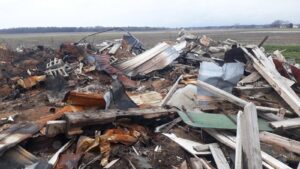 A large pile of burnt debris from a fire cleanup job in a field, handled by AAA Rousse Junk Removal Services Inc of Florida in Tampa, FL.