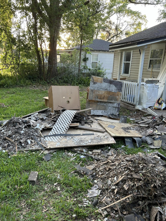 A large pile of construction and yard debris next to a house, ready for removal by Just Dump It in Jacksonville, FL.