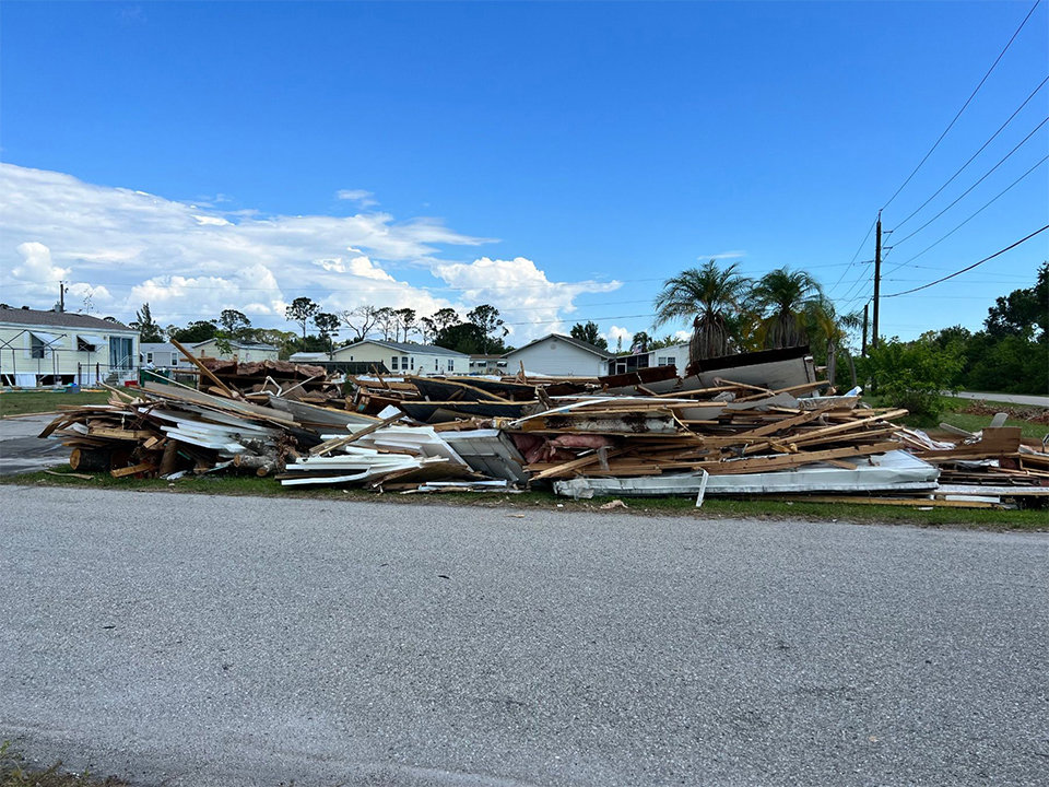 A large pile of construction and demolition debris on the side of a road, ready for cleanup by AAA Rousse Junk Removal Services Inc of Florida in Tampa, FL.