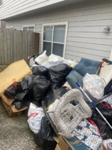 A large pile of household junk including trash bags, cushions, and old furniture outside a home for Handymen Junk Removal in Houston, TX.