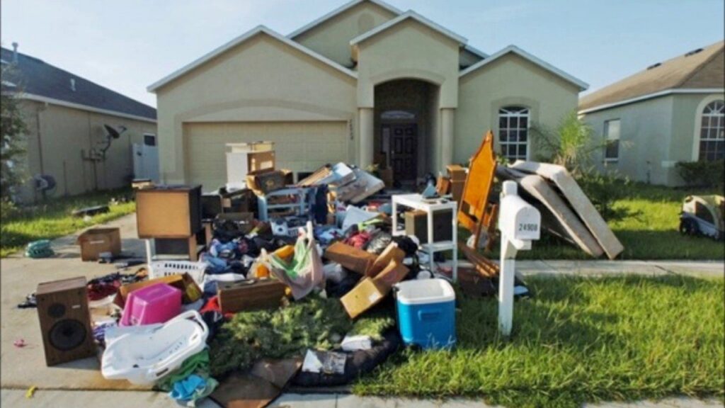 A large pile of household junk, including furniture and boxes, in front of a residential house for A1 Junk Removal Of Tucson, AZ.