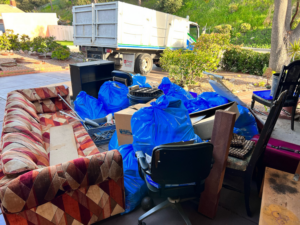 A large pile of household junk, including a sofa and bagged items, ready for Republic Junk Removal in San Diego, CA.