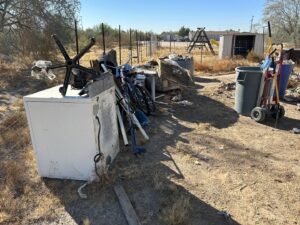 A large pile of various junk items, including a refrigerator and bicycle, awaiting removal by Skunky's Junk Removal in Tempe, AZ.