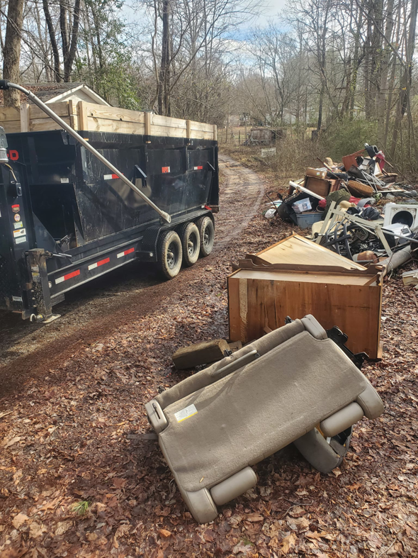 A large pile of household junk and debris next to a dumpster trailer, awaiting removal by Standard Dumpster LLC in Rock Hill, SC.