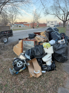 A large pile of household junk, including bags, furniture, and a toilet, awaiting pickup by Next Level Waste Group LLC in Kansas City, MO.