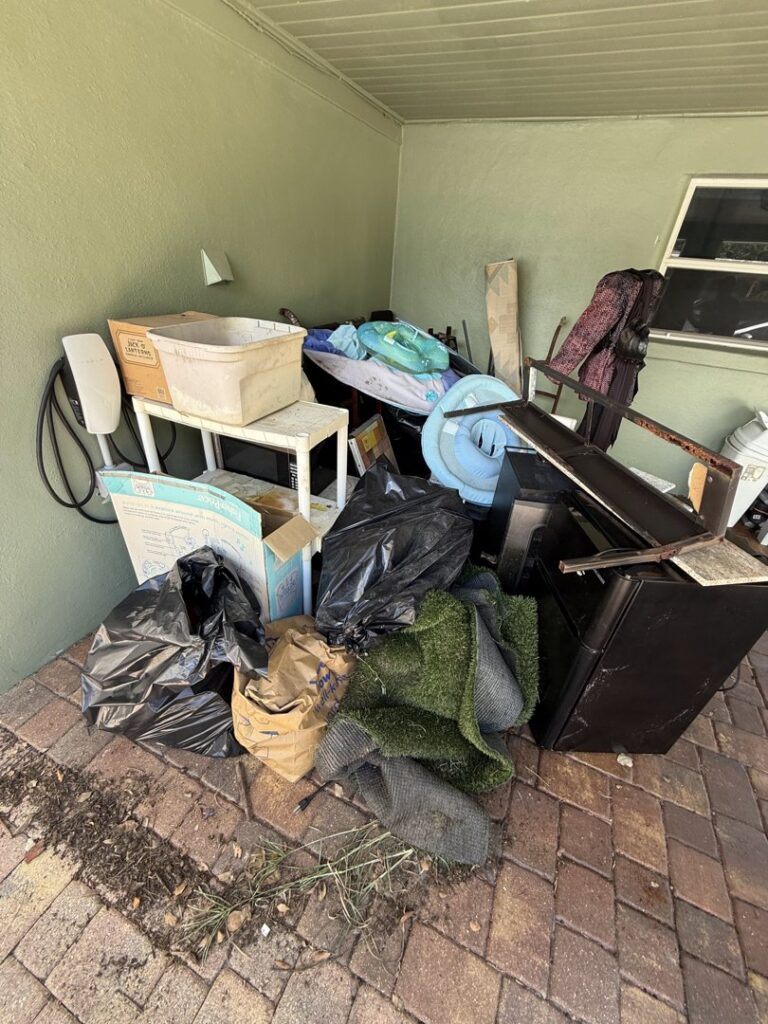 A large pile of miscellaneous junk, including bags, boxes, and furniture, on a patio awaiting removal by Lightning Bay Junk Removal in Tampa, FL.