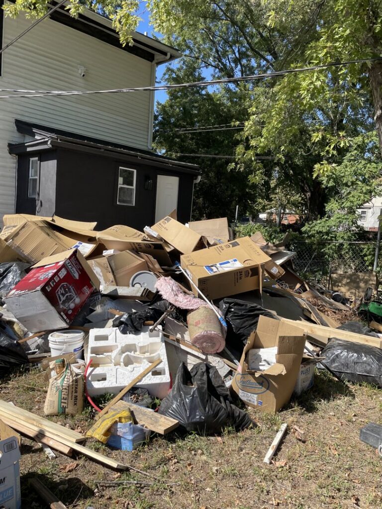 A large pile of various junk and debris outside a house, showing a comprehensive cleanout service by Little Tykes Property Preservation in Independence, MO.