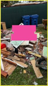 A large pile of mixed junk and construction debris in a yard, ready for pickup by Junk Be Gone in Miami, FL.