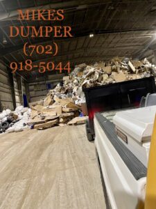 A large pile of old couch cushions and household items left under a tree for junk removal by Mike's Dumper in Las Vegas, NV.