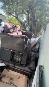 A large pile of old sofas and furniture stacked outdoors, awaiting pickup by Junk Be Gone in Miami, FL.