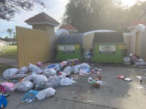 A large pile of general trash and two dumpsters overflowing with waste, awaiting removal by JJ's Waste & Recycling in Orlando, FL.