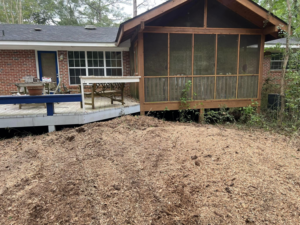 A large pile of fresh wood chips next to a residential deck, showing the result of stump grinding by Manley's Stump Grinding in Opelika, AL.