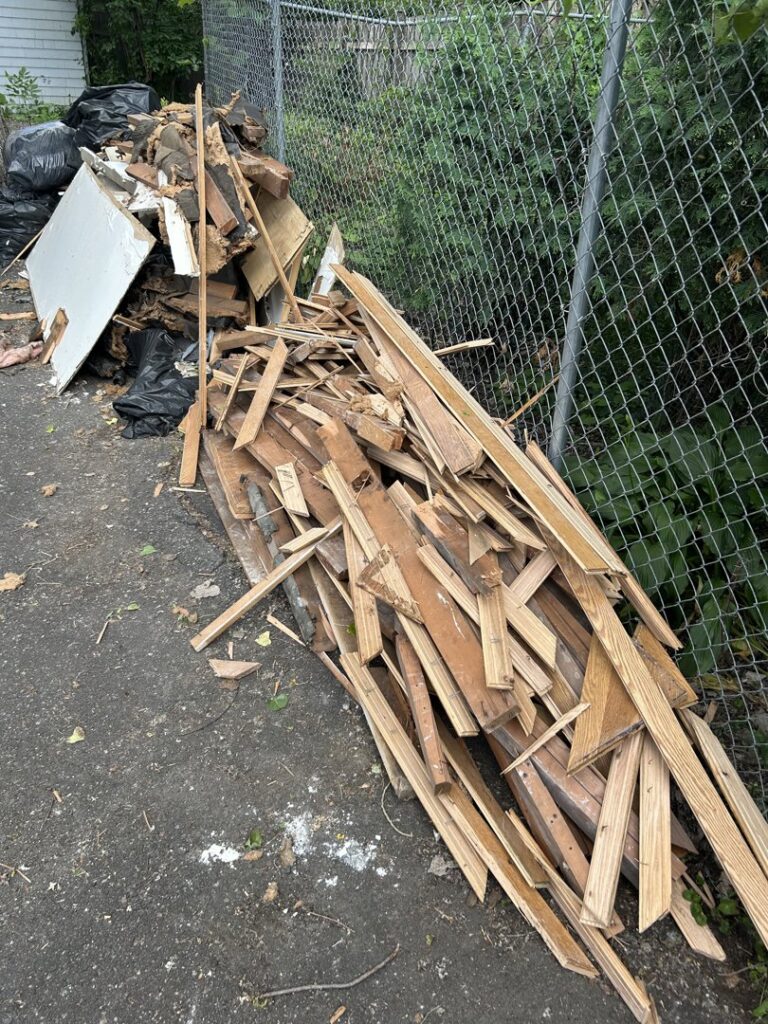 A large pile of wood debris and trash bags awaiting removal by Mr. Groundhog Disposal and Services in Bloomington, MN.