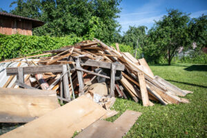 A large pile of wood and construction debris in a grassy yard, indicating a need for junk removal services by Dumpster 360 in Clarksville, TN.