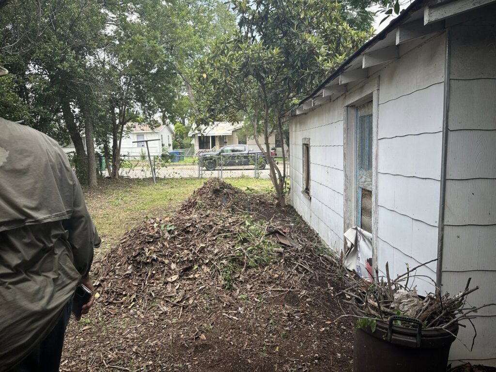 A large pile of leaves, branches, and dirt next to a house, for Silverhull Junk Removal in San Antonio, TX