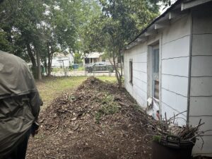 A large pile of leaves, branches, and dirt next to a house, for Silverhull Junk Removal in San Antonio, TX