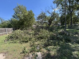 A large pile of tree branches and green waste in a yard, ready for removal in Wichita, KS.