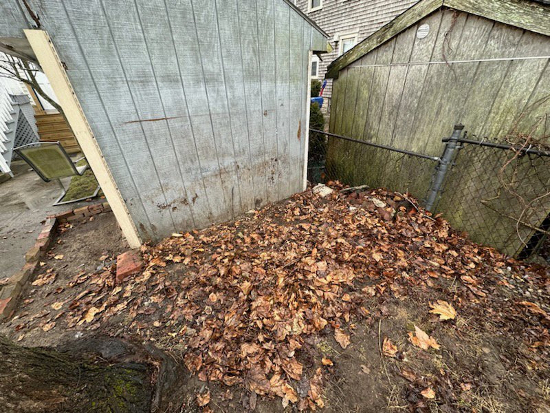 A large pile of wood, construction materials, and black trash bags awaiting junk removal by CK Junk Removal in New Bedford, MA