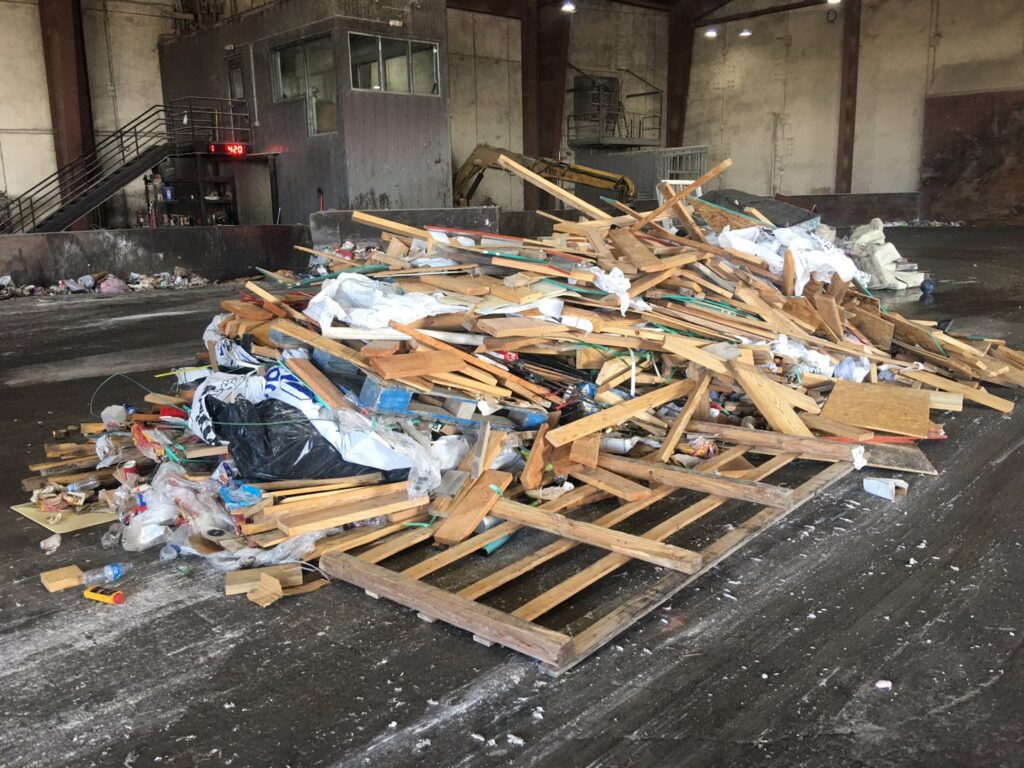 A large pile of wood and mixed debris on a concrete floor, ready for junk removal by Liberty Hill Dumpster Rental in Austin, TX