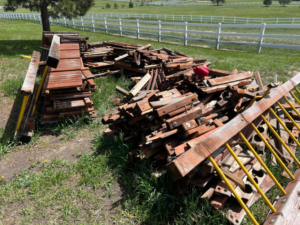A large pile of wooden debris and old lumber in a grassy yard, ready for removal by Mile High Junk in Aurora, CO.