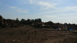 Large piles of wood debris and general junk at a waste processing site for West Coast Waste in Fresno, CA.