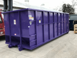 A large purple roll-off dumpster from Rock Acres Companies in a yard in Kansas City, MO.