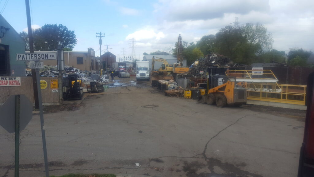 A wide view of the large recycling yard operations with heavy equipment and scrap piles at David Hirschberg Steel & Recycling Center in Cincinnati, OH.