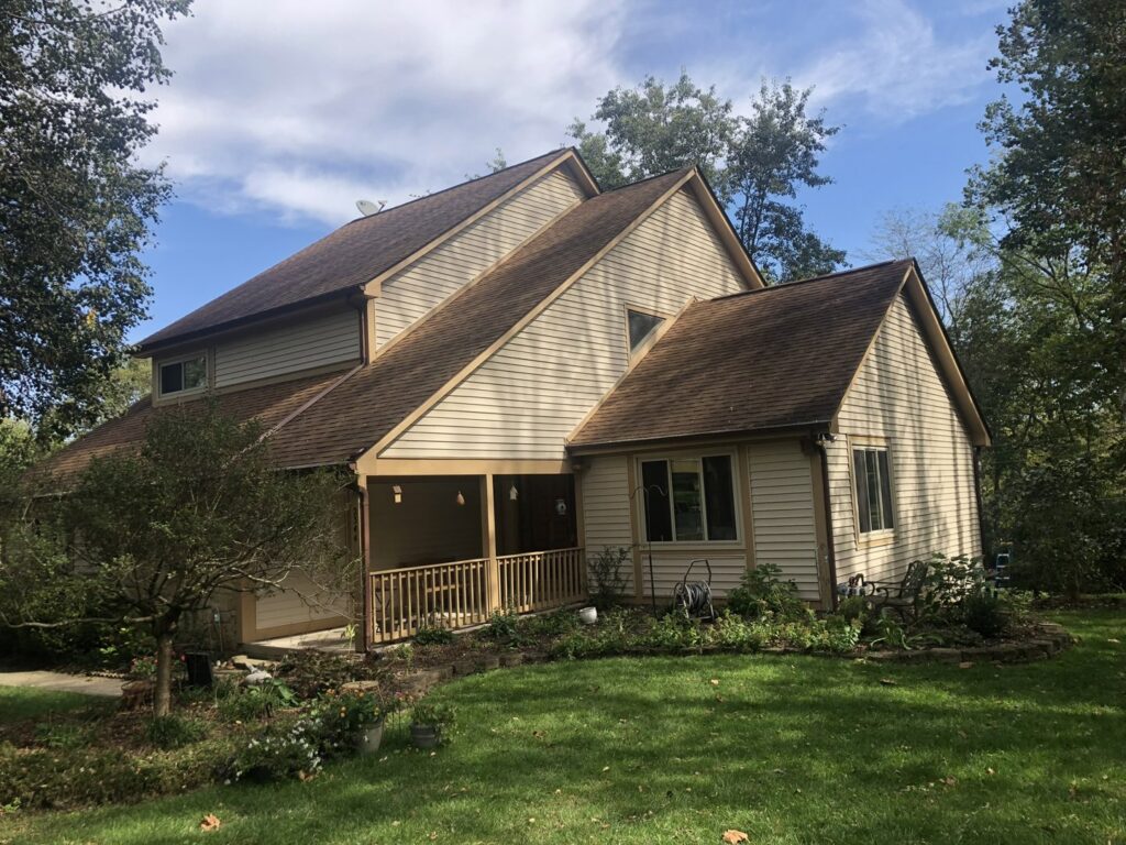 A large residential house with a newly installed brown shingle roof and light-colored siding by Mp painting and roofing LLC in Dayton, OH