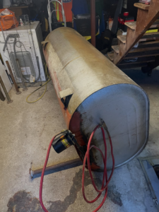 A large, rusty tank with hoses attached, lying on its side, ready for removal by DLS Junk Removal in Waterbury, CT.