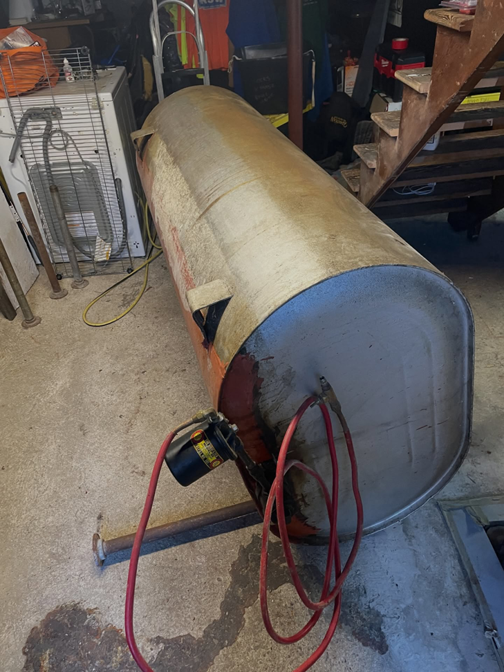 A large, rusty tank with hoses attached, lying on its side, ready for removal by DLS Junk Removal in Waterbury, CT.