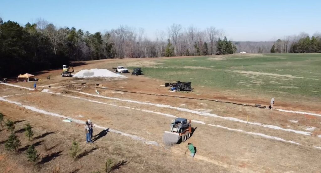 A large-scale drainage excavation project with equipment in a field by Drip Dry Drainage in Cramerton, NC.