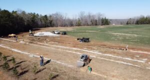 A large-scale drainage excavation project with equipment in a field by Drip Dry Drainage in Cramerton, NC.