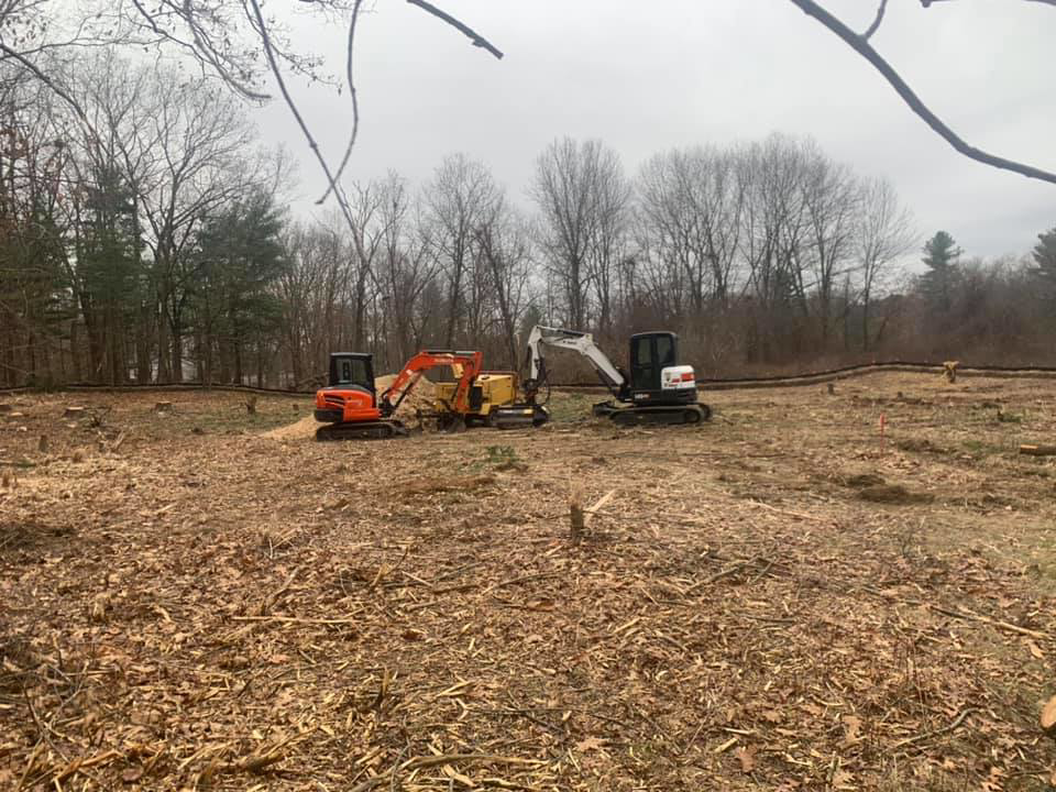 Multiple excavators on a cleared area with stumps and wood chips, showing land clearing by L & P Excavation and Tree Removal in Salem, NH.