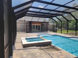 A large, well-constructed screened pool enclosure with a pool and hot tub, installed by Cover Works in Luling, LA.