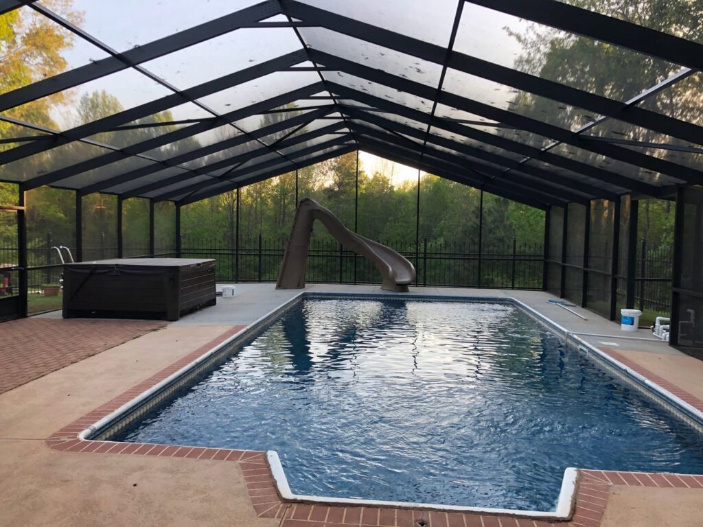 A large screened enclosure covering a swimming pool and hot tub by Four Seasons of River City in Columbus, GA.