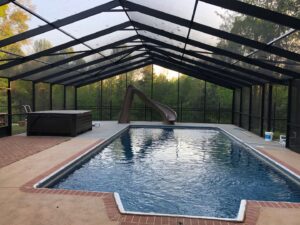 A large screened enclosure covering a swimming pool and hot tub by Four Seasons of River City in Columbus, GA.