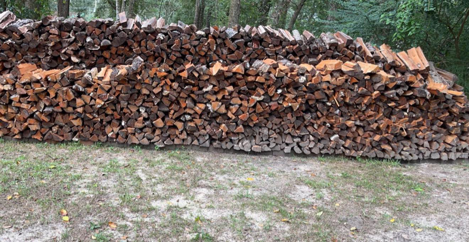 A large, neatly stacked pile of firewood from tree removal services by Hansen Tree Service in Abington, MA.