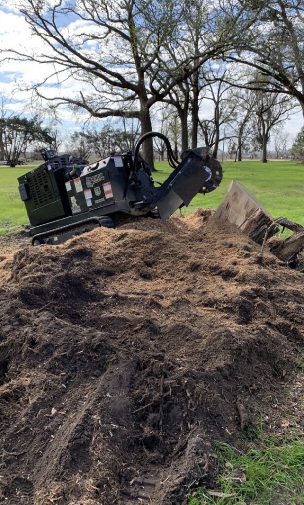 A stump grinder machine next to a large pile of wood chips and dirt from a recent stump removal by Stumps Be Gone in Augusta, GA.