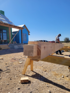 A large timber beam resting on sawhorses at a construction site, part of a project by Hill Country Framing in Austin, TX