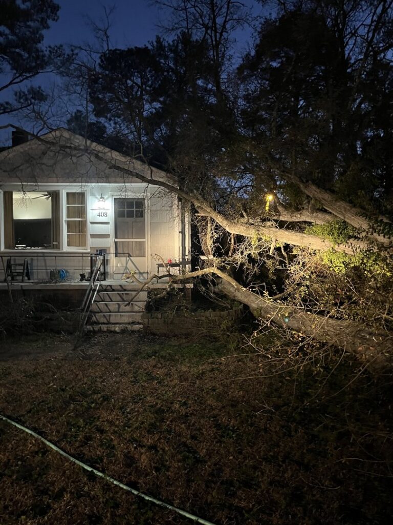 A large tree fallen onto a house at night, showing emergency storm damage response by Arbor Elite SC in Columbia, SC.