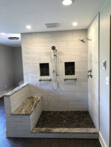 A large walk-in shower with accessible design and a granite bench by Shafer Construction, LLC in Bethlehem, PA.