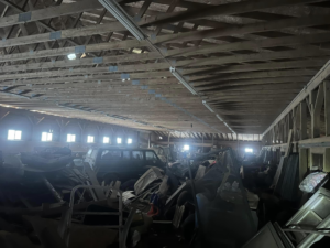 A wide view of a large, cluttered warehouse filled with junk, ready for general junk removal by White Dumpster in Alliance, OH.